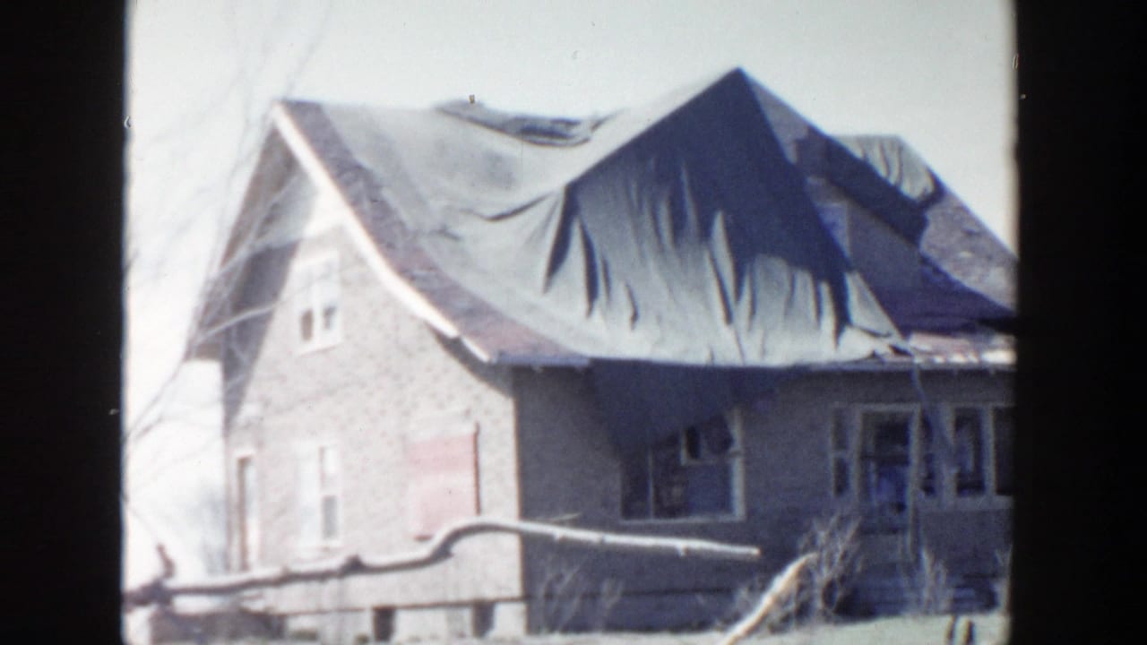 Damaged chapel exterior with tarp-covered roof and broken windows.