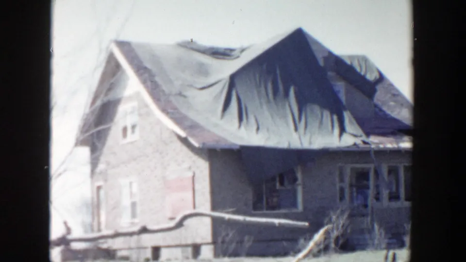 1956 Grand Rapids home-movie frame showing the abandoned Standale Chapel exterior with a torn roof covering and damaged windows.