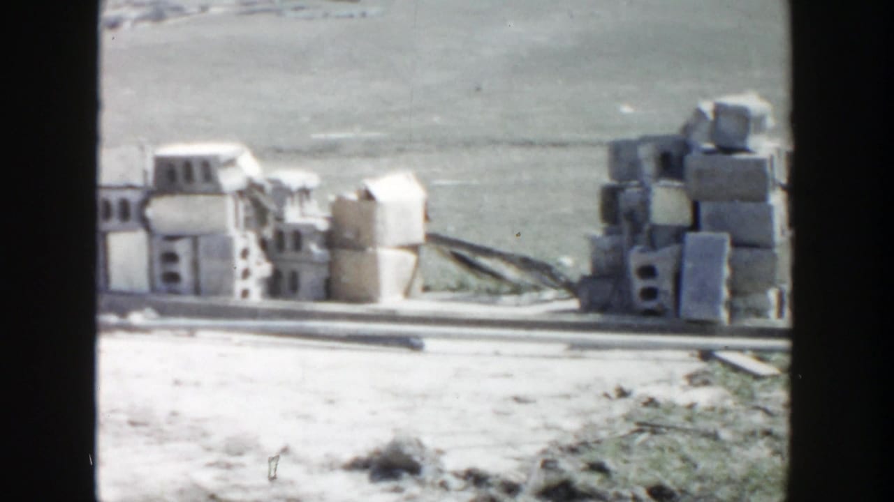 Stacks of blocks and construction debris beside a partially framed site.