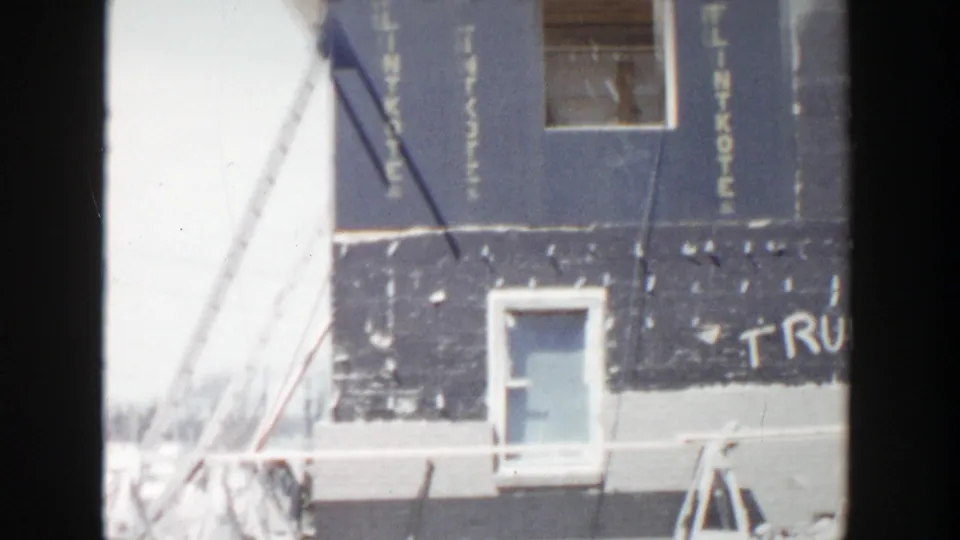 Grand Rapids construction scene with temporary bracing, a doorway, blue-gray sheathing, and part of the Trudy Tony graffiti visible.