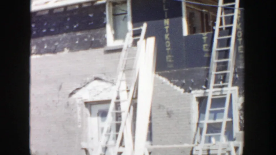Grand Rapids construction frame with a ladder crossing an unfinished wall and LINTKOTE lettering along dark sheathing.