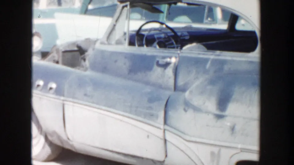 Final 1956 Grand Rapids frame showing the parked two-tone car with an open door and a partial view of the interior.