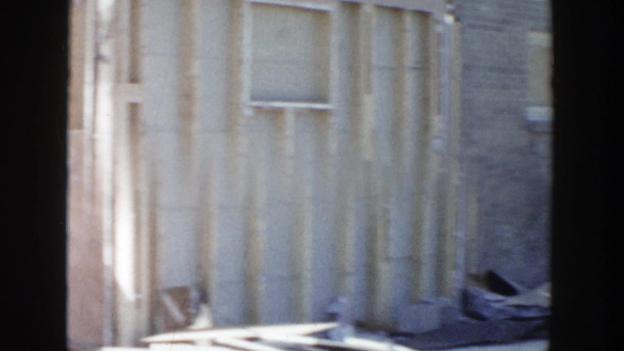 Damaged wall framing and siding seen through dark film borders.
