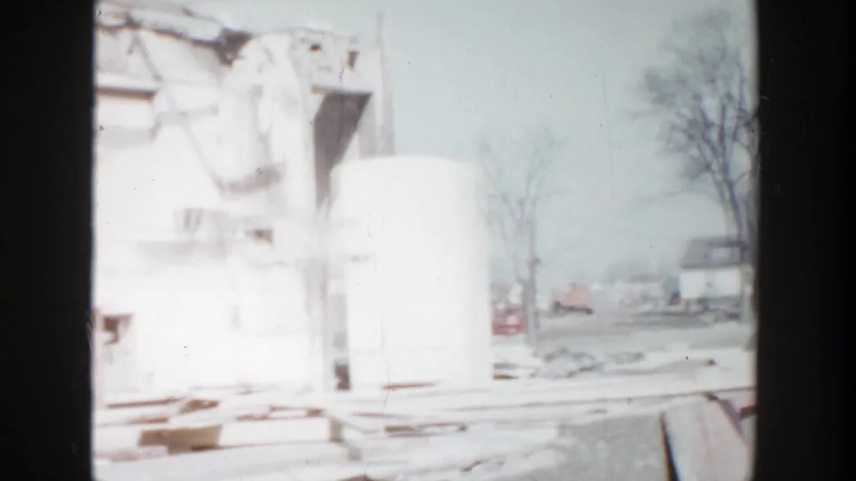White unfinished building section in Grand Rapids, Michigan, with exposed openings and construction debris in a pale 8mm frame.