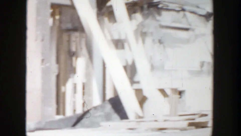 Close 8mm view of a Grand Rapids construction area with white bracing, wall sections, and boards lying near the structure.