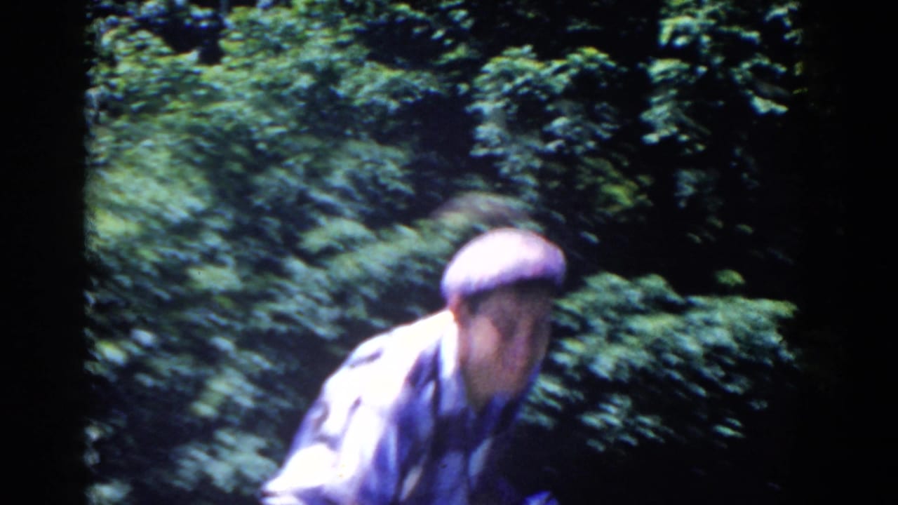 In 1958 French Lick home-movie footage, a young man in a cap and plaid shirt moves close to the camera near leafy trees.