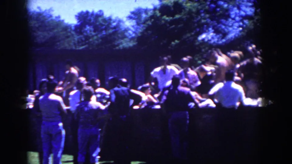 The home-movie view shows a larger cluster of spectators near the wall as the outdoor catch activity continues on the lawn.