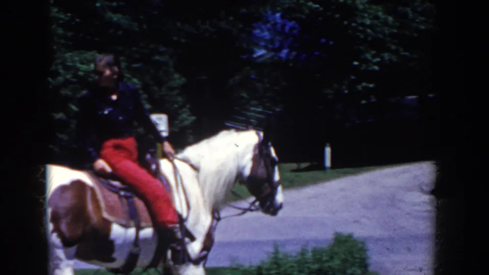 The rider in red pants continues along a park path on a pinto horse in the 1958 French Lick home-movie footage.