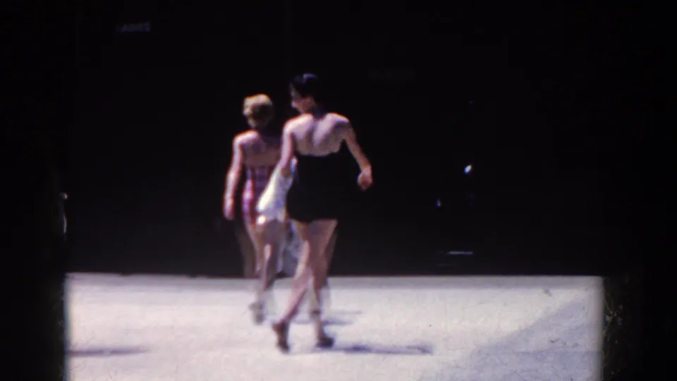 Two adult women in swimsuits walk away from the camera in the 1958 French Lick beach or resort scene.