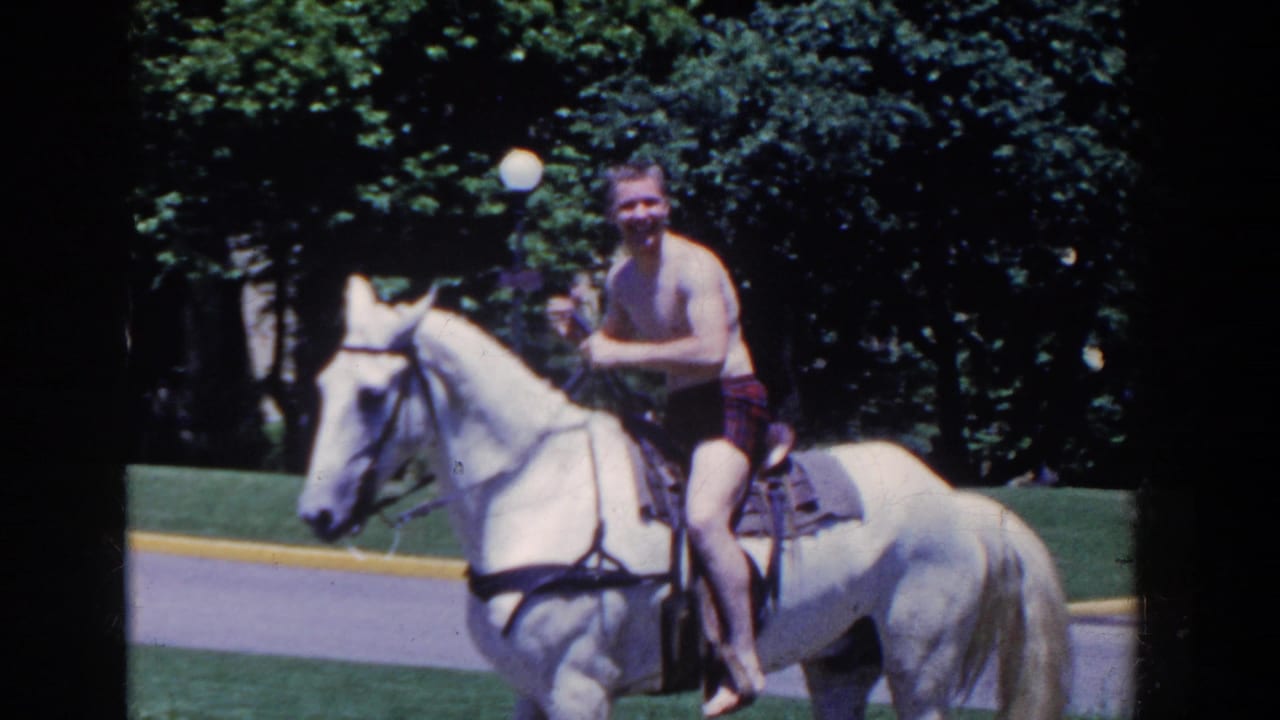 The rider looks toward the camera while seated on a white horse in the French Lick park setting.