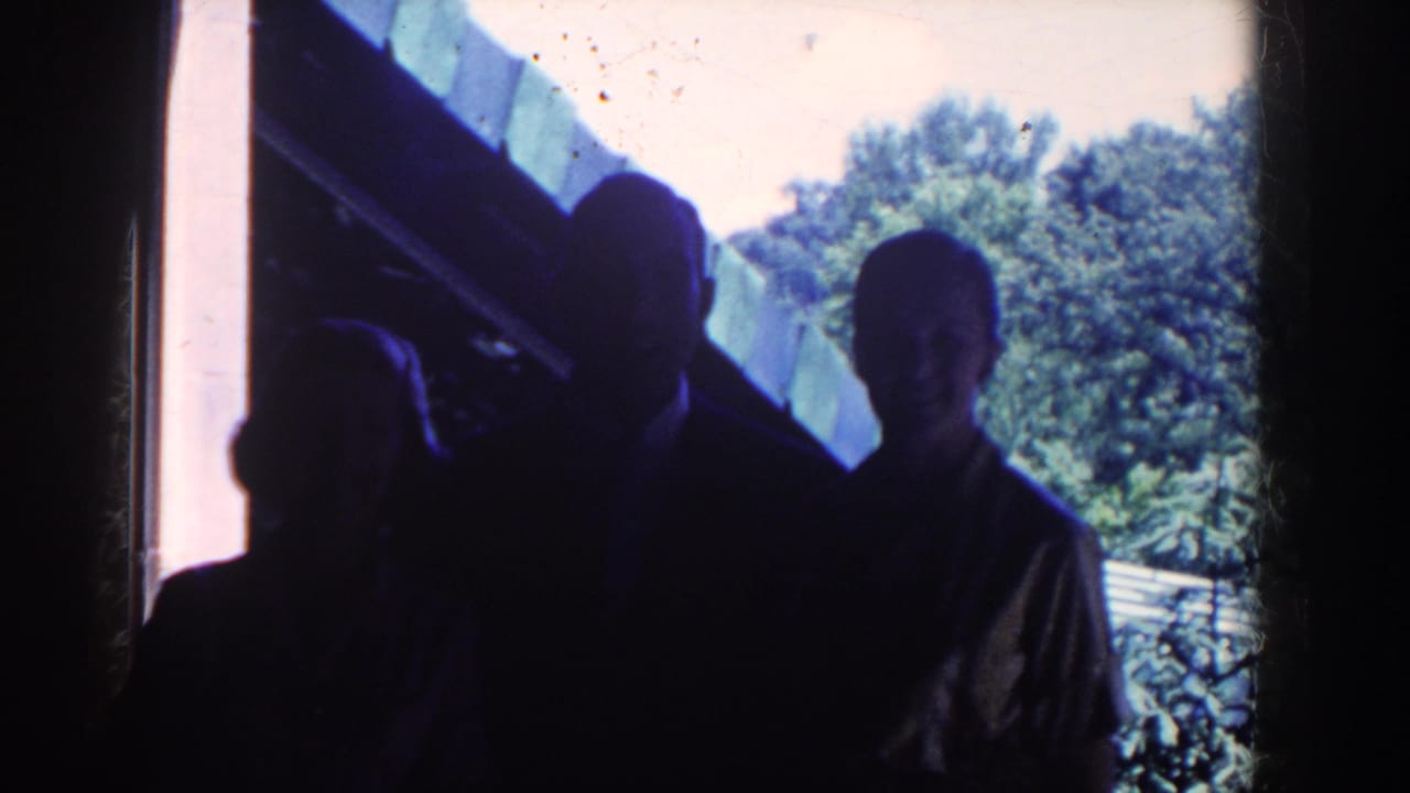 In 1958 French Lick home-movie footage, silhouetted figures stand inside near a bright window looking out toward trees.