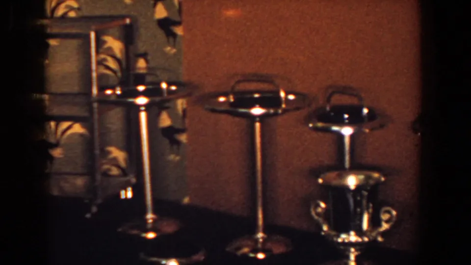 A trophy cup and several gold-toned ashtrays sit on a dark tabletop in a private French Lick interior from 1958.