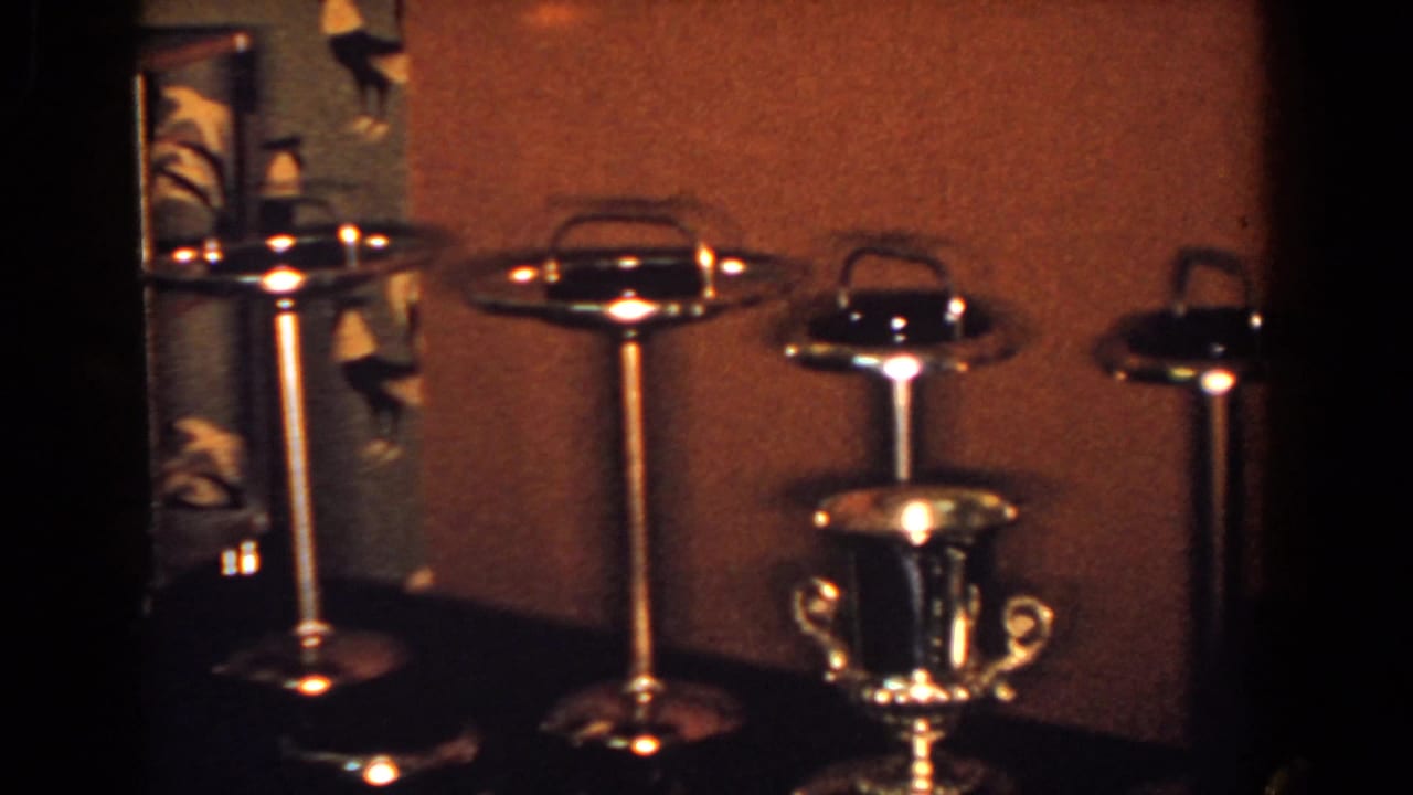 Silver-toned pedestal ashtrays and a small trophy-style cup on a dark surface.