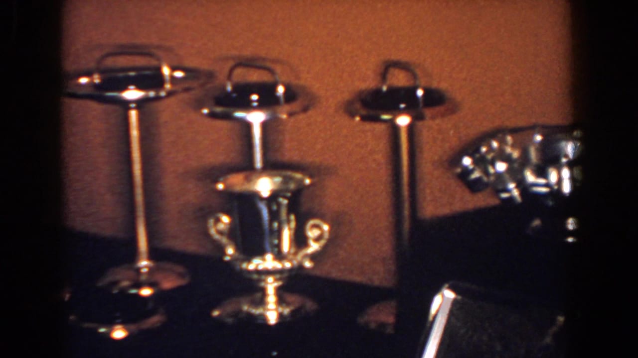 1958 French Lick frame with silver-toned ashtrays, a small handled cup, and the edge of a decorative bowl.