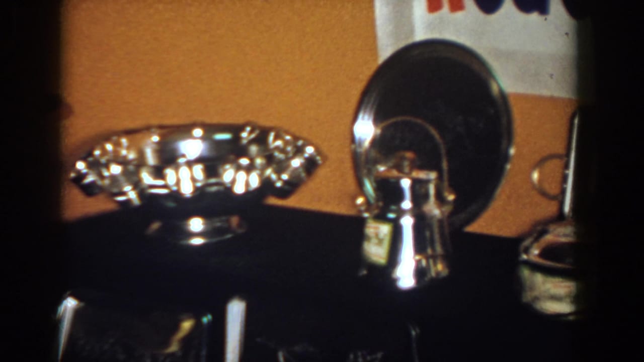 Close 1958 home-movie view of polished silver awards on a dark console in French Lick, Indiana.