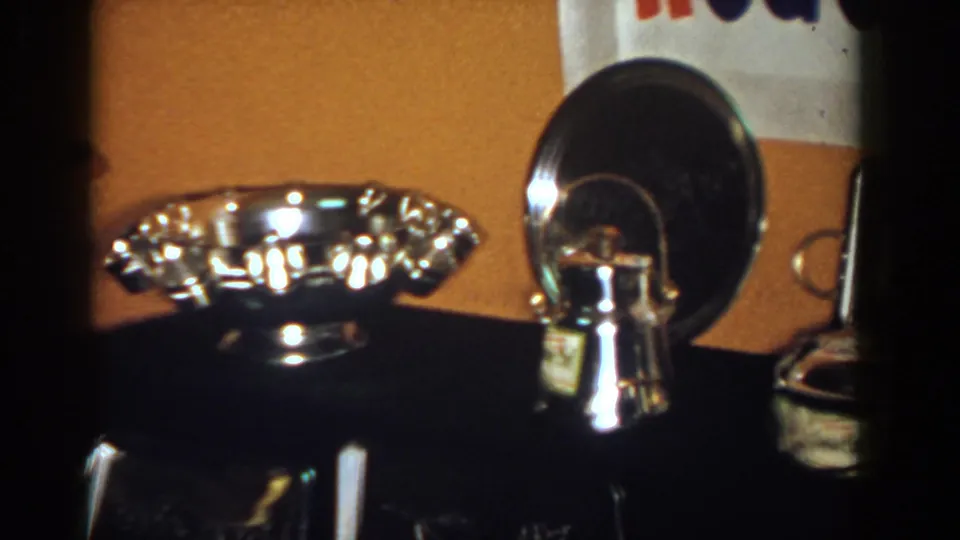 Close 1958 home-movie view of polished silver awards on a dark console in French Lick, Indiana.