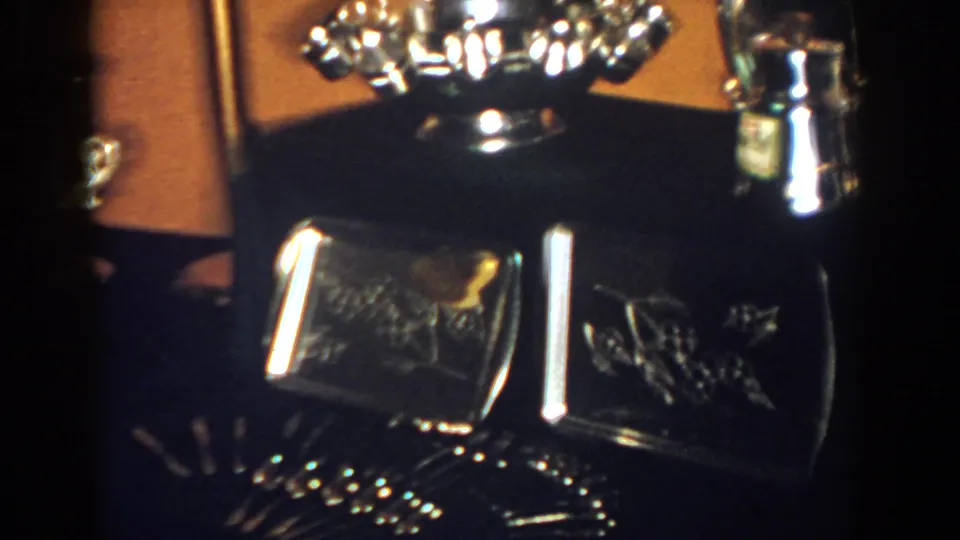 A close 1958 home-movie frame shows silver awards and dark glass boxes on a console table in French Lick.