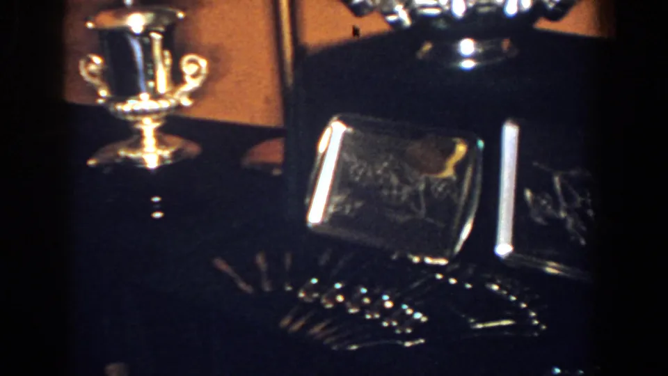 1958 French Lick frame with a gold-toned cup, silver bowl, and dark glass awards on an indoor console.