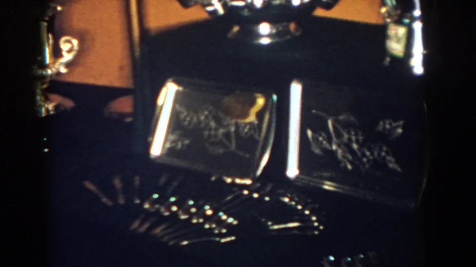 A closer 1958 frame shows engraved rectangular metal cases with smaller polished pieces and reflections across a dark display surface.
