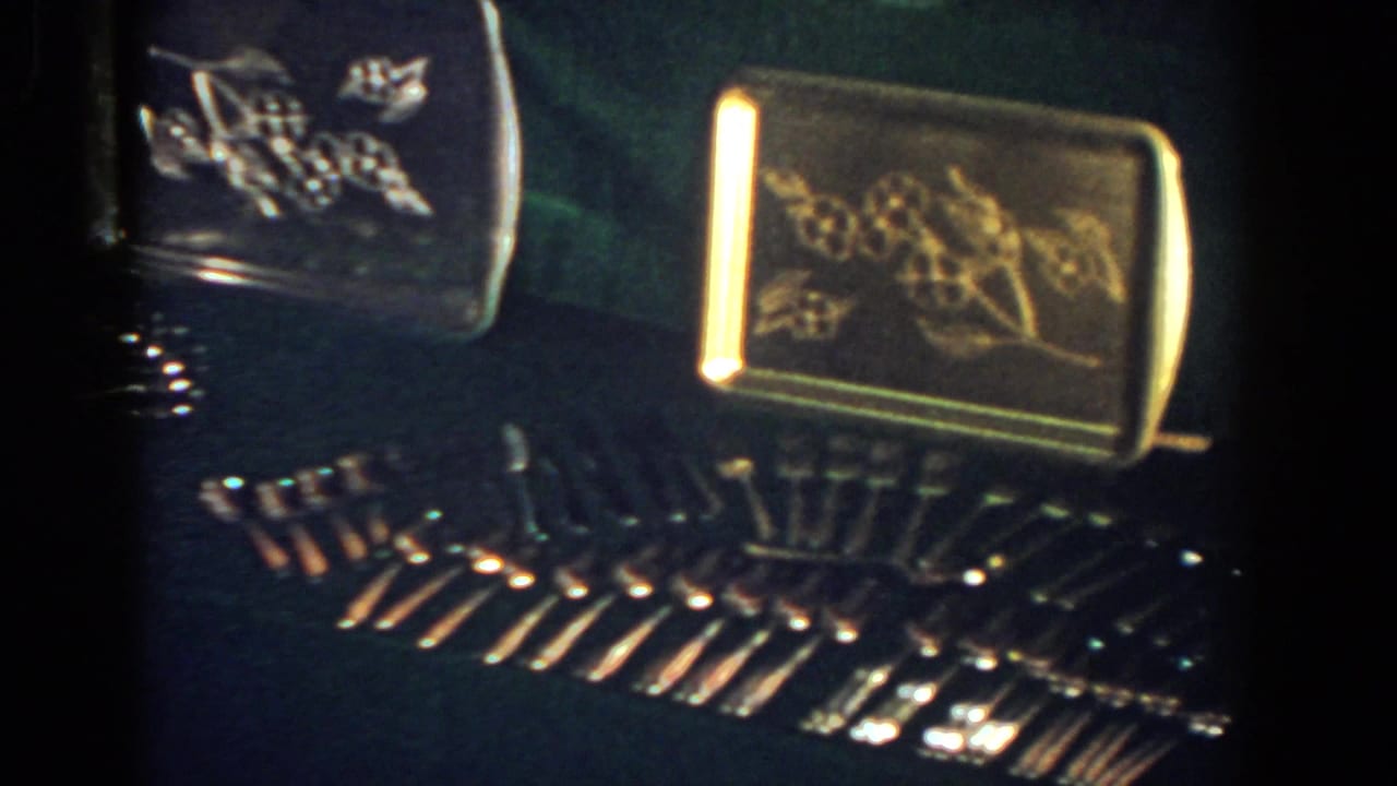 Gold-toned engraved trays above rows of shiny stemware on a dark surface.