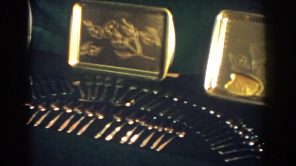 1958 French Lick 8mm frame with engraved gold-toned trays and neatly arranged reflective stemware on a dark surface.