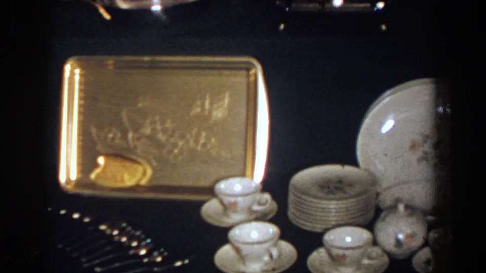 1958 French Lick 8mm frame with white porcelain teacups, stacked plates, a rounded porcelain piece, and a gold-toned tray.