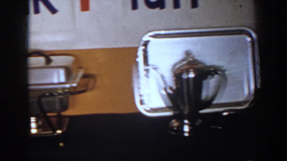 1958 French Lick home-movie view of a silver teapot before a serving tray, with china and a chafing dish nearby.