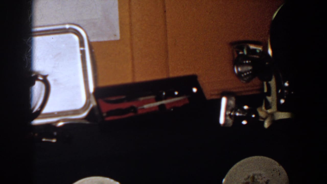 1958 French Lick home-movie frame showing a silver tray and other reflective metal objects on a dark surface.