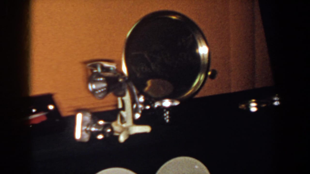 Close 8mm view of a chrome-framed round mirror and small metal object in a dim French Lick interior.