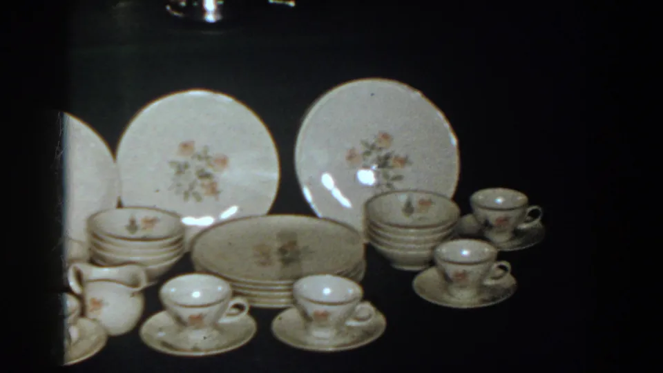 1958 French Lick frame showing floral plates, stacked dishes, cups, saucers, and a small pitcher or creamer in the dinnerware set.