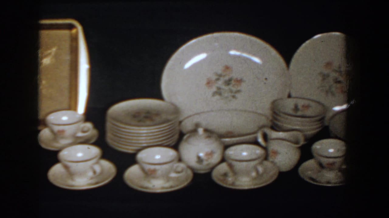 Porcelain cups, saucers, stacked plates, serving pieces, and a gold-toned tray on display.