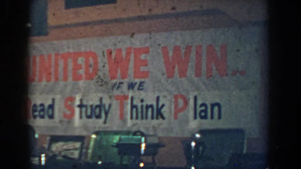 1958 French Lick home-movie frame showing a poster with United We Win lettering and the words Read, Study, Think, and Plan.