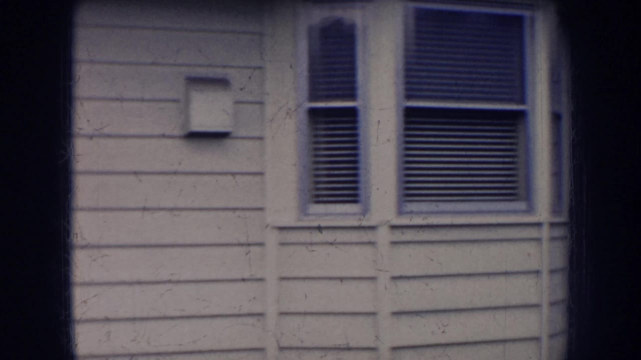 1956 Nebraska exterior view of a light-sided house wall with a small fixture and window blinds.