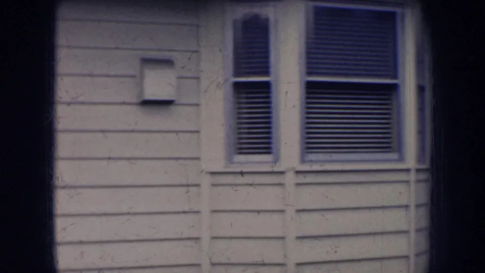 1956 Nebraska exterior view of a light-sided house wall with a small fixture and window blinds.