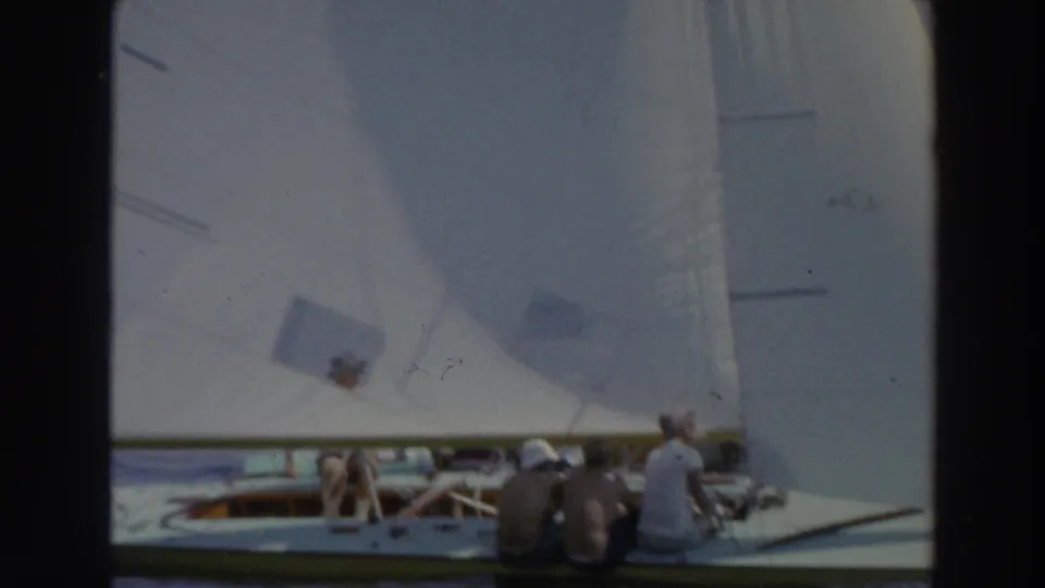 1966 Wisconsin home-movie frame with several people aboard small sailboats under close white sails on lake water.