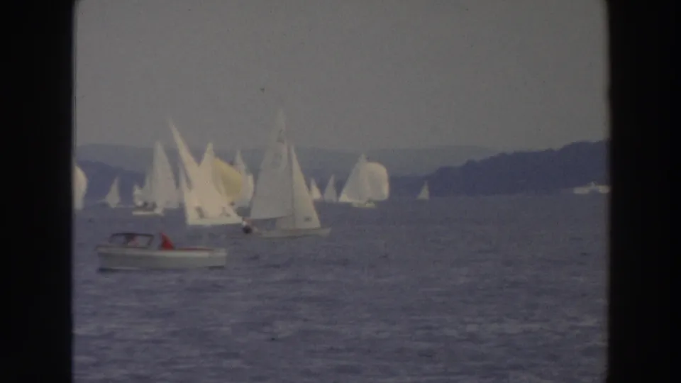 1966 Wisconsin 8mm frame with a foreground motorboat and several sailboats across the water.