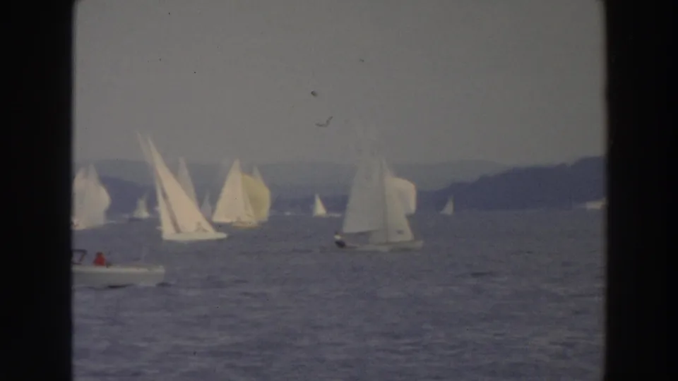 1966 Wisconsin lake regatta frame showing sailboats and a small motorboat under a gray sky.