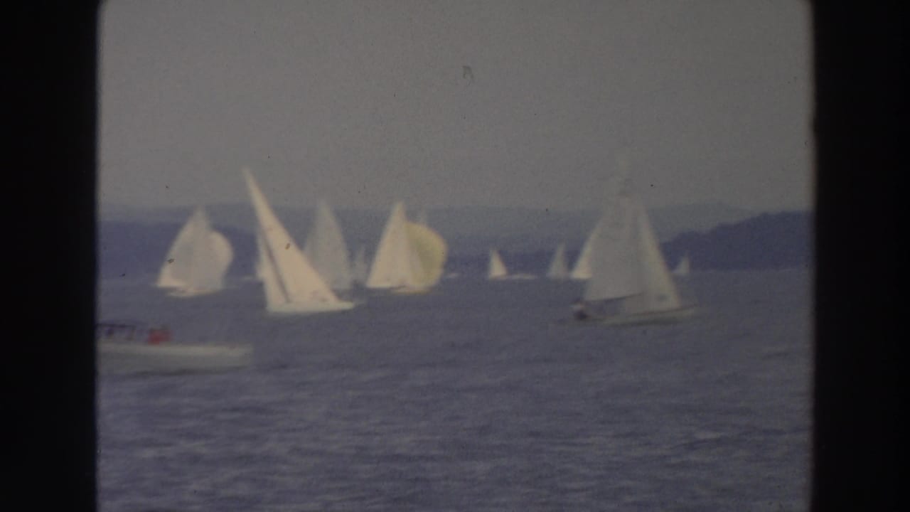 1966 Wisconsin 8mm frame showing a small motorboat near a scattered group of white sailboats on a lake.