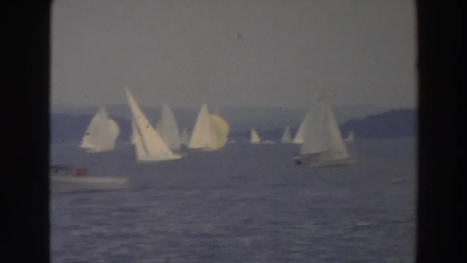1966 Wisconsin 8mm frame showing a small motorboat near a scattered group of white sailboats on a lake.