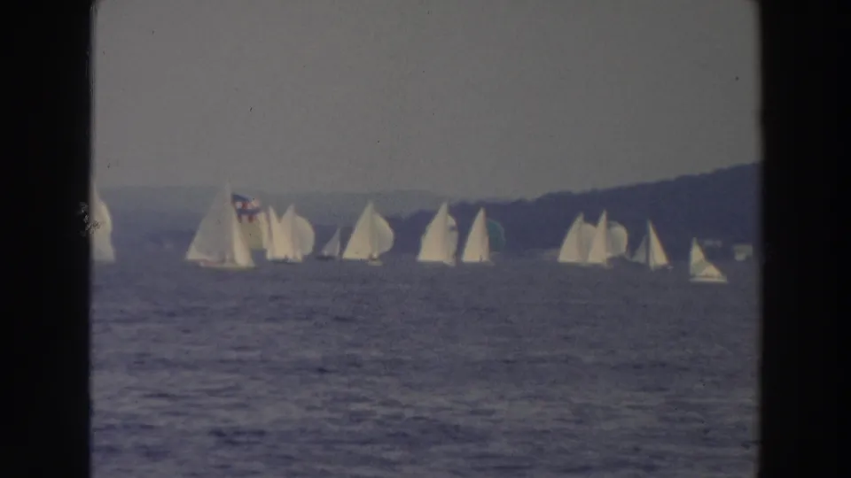 Soft 8mm Wisconsin sailing scene from 1966, with white boats clustered on the lake and shoreline visible beyond.
