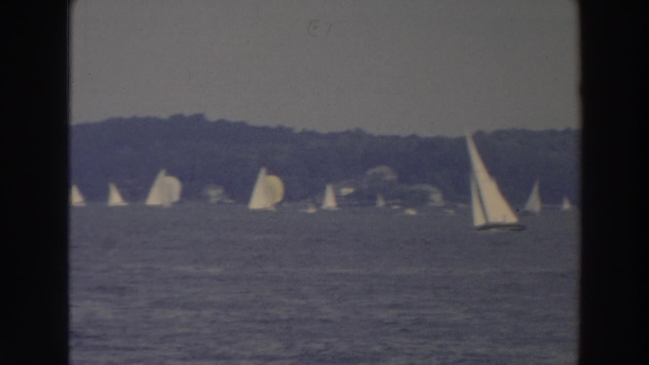Wide lake view with several distant sailboats and one larger sailboat near the right edge.