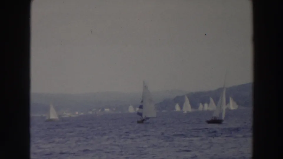 Wide 8mm view of multiple sailboats gliding across a Wisconsin lake, with muted color and soft focus.