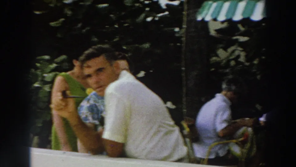 1966 Wisconsin vacation frame with a man leaning at the railing, visitors behind him, and a sailor partly visible at right.