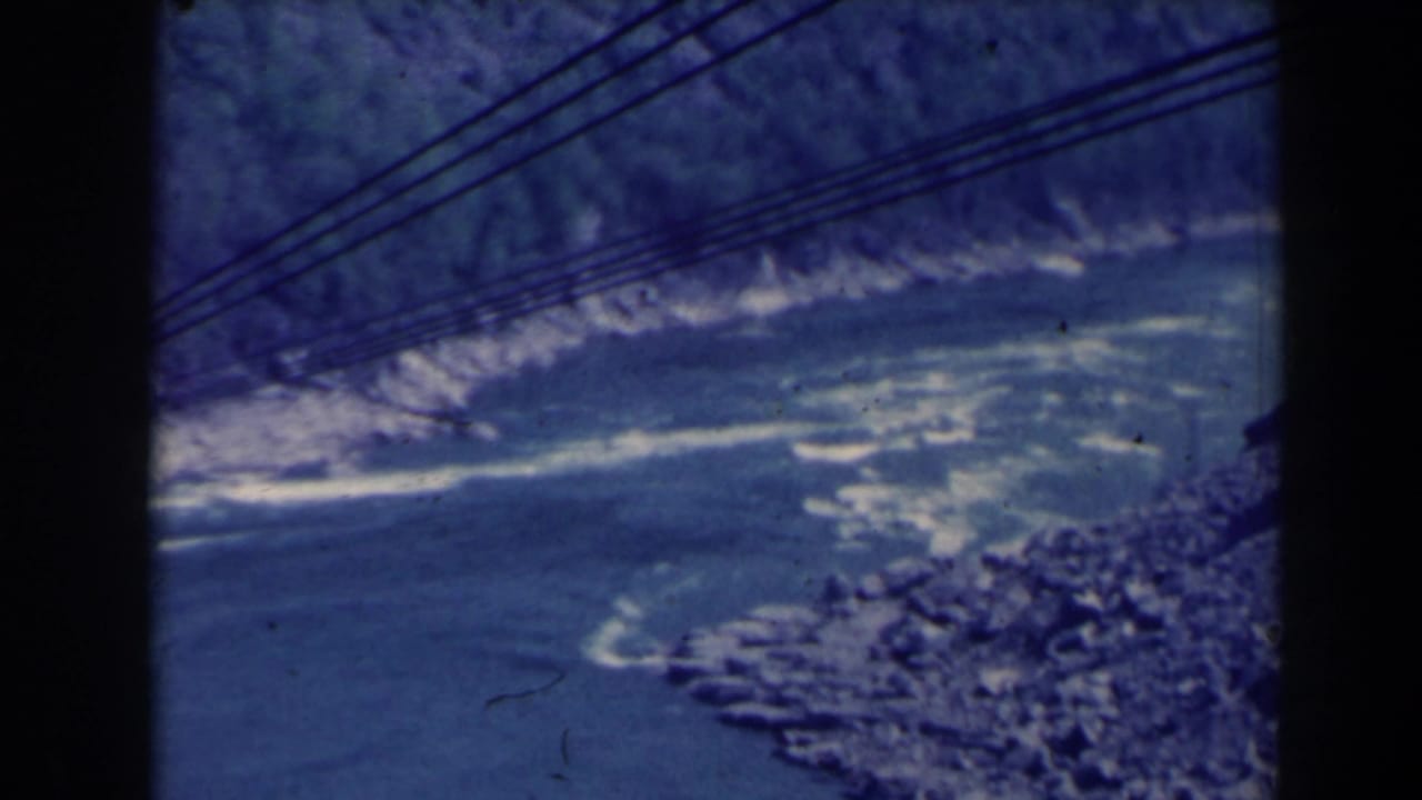 River rapids and rocky gorge seen beneath several diagonal cable lines.
