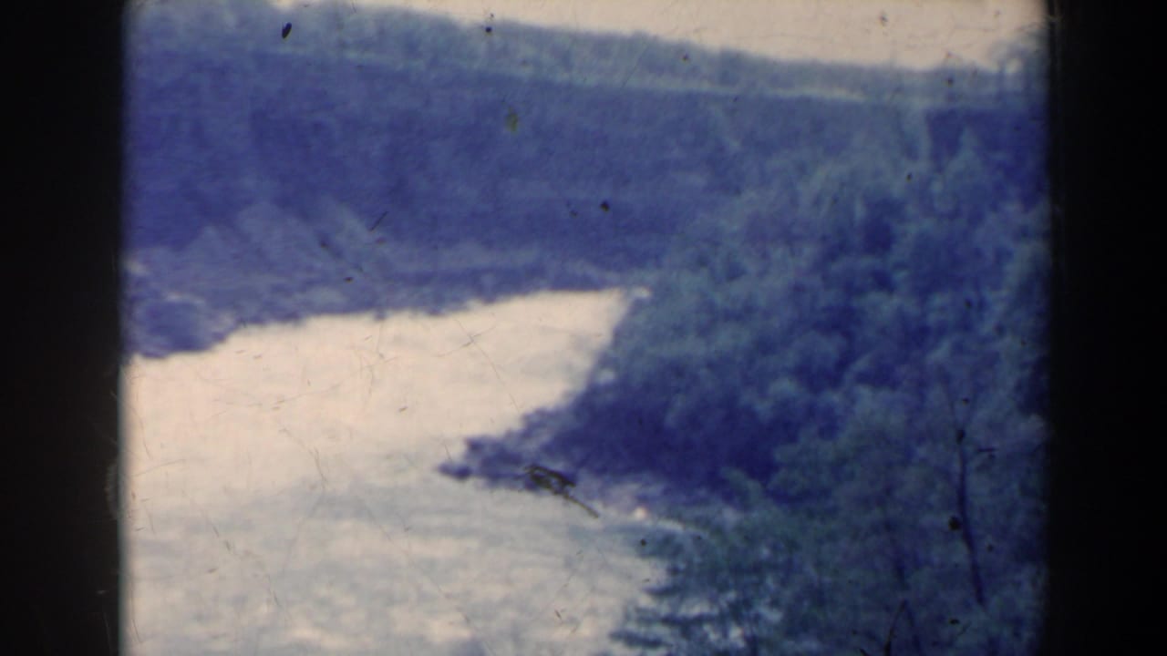Wide river curving between dense forested banks with dark 8mm frame borders.