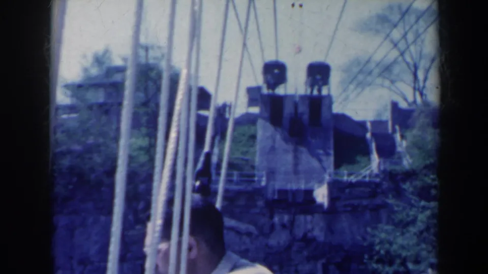 1963 Niagara Falls, Canada home-movie frame showing a man in profile near industrial machinery and vertical bridge supports.