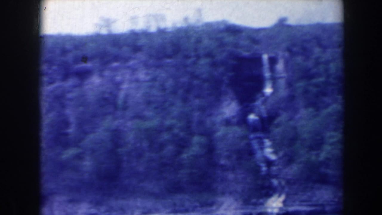 Waterfall and wooded cliff viewed from across water, with dark contact-sheet borders.