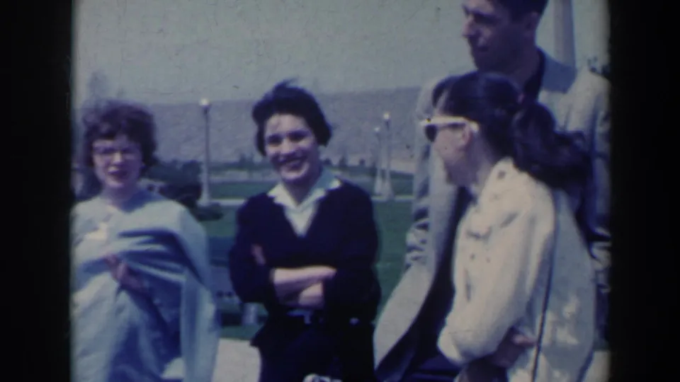 1963 Niagara Falls frame of friends in sweaters and sunglasses smiling and standing together outdoors.
