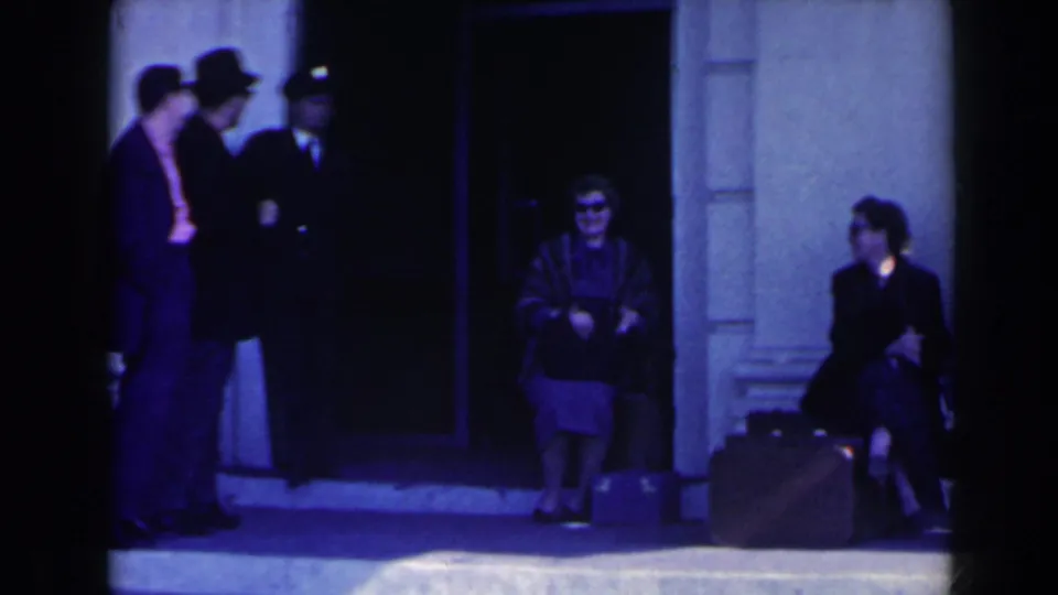 1963 Niagara Falls, Canada frame of travelers outside the Hotel Sheraton-Brock entrance, with luggage and seated women visible.