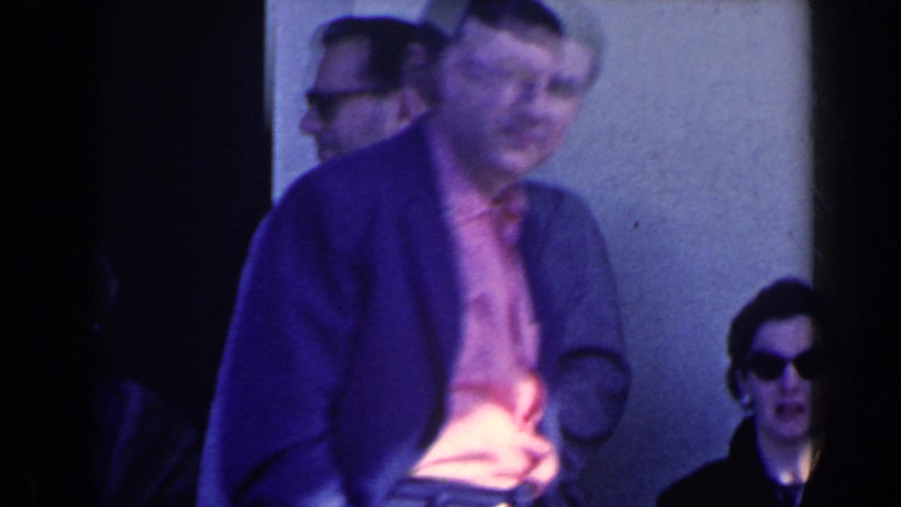 1963 home-movie frame from Niagara Falls, Canada showing people outside a building as a man passes close to the camera.